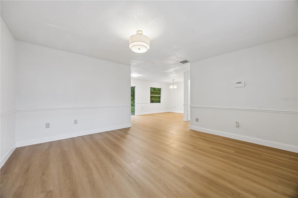 An empty room with light wood-look flooring, white walls, and chair rail molding — 3688 RUNDO DRIVE, ORLANDO, FL