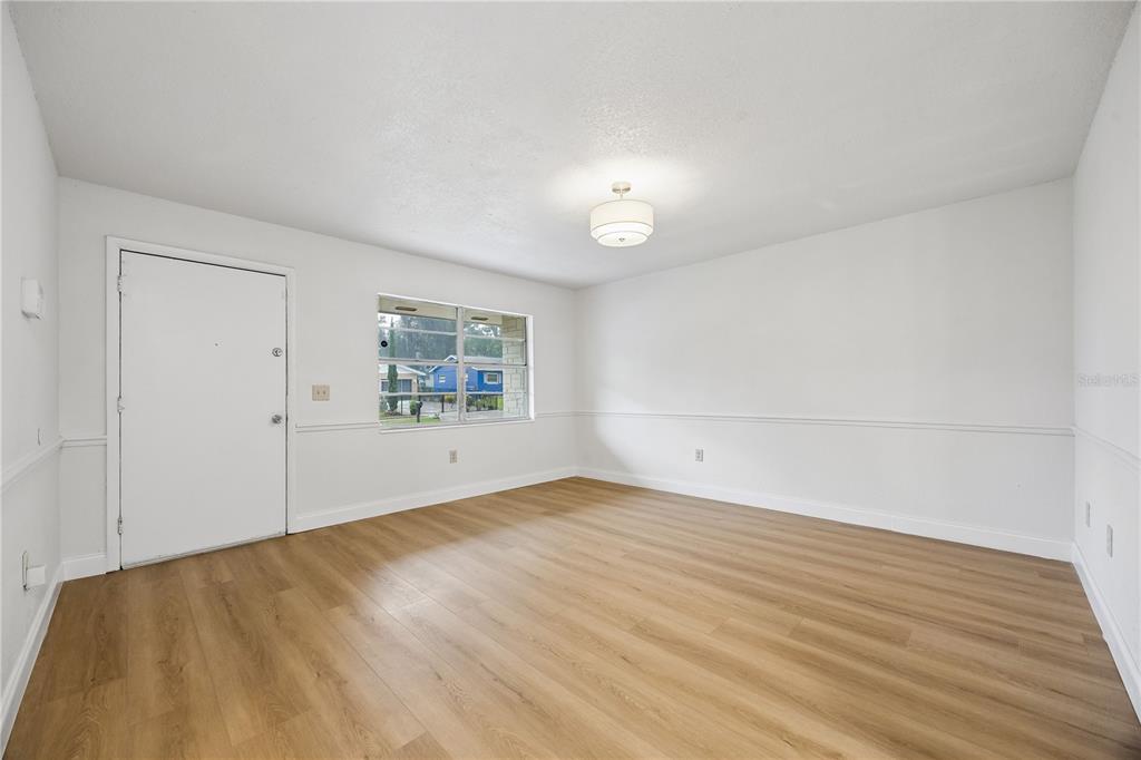 An empty room with white walls, chair rail molding, light wood flooring, and a window — 3688 RUNDO DRIVE, ORLANDO, FL
