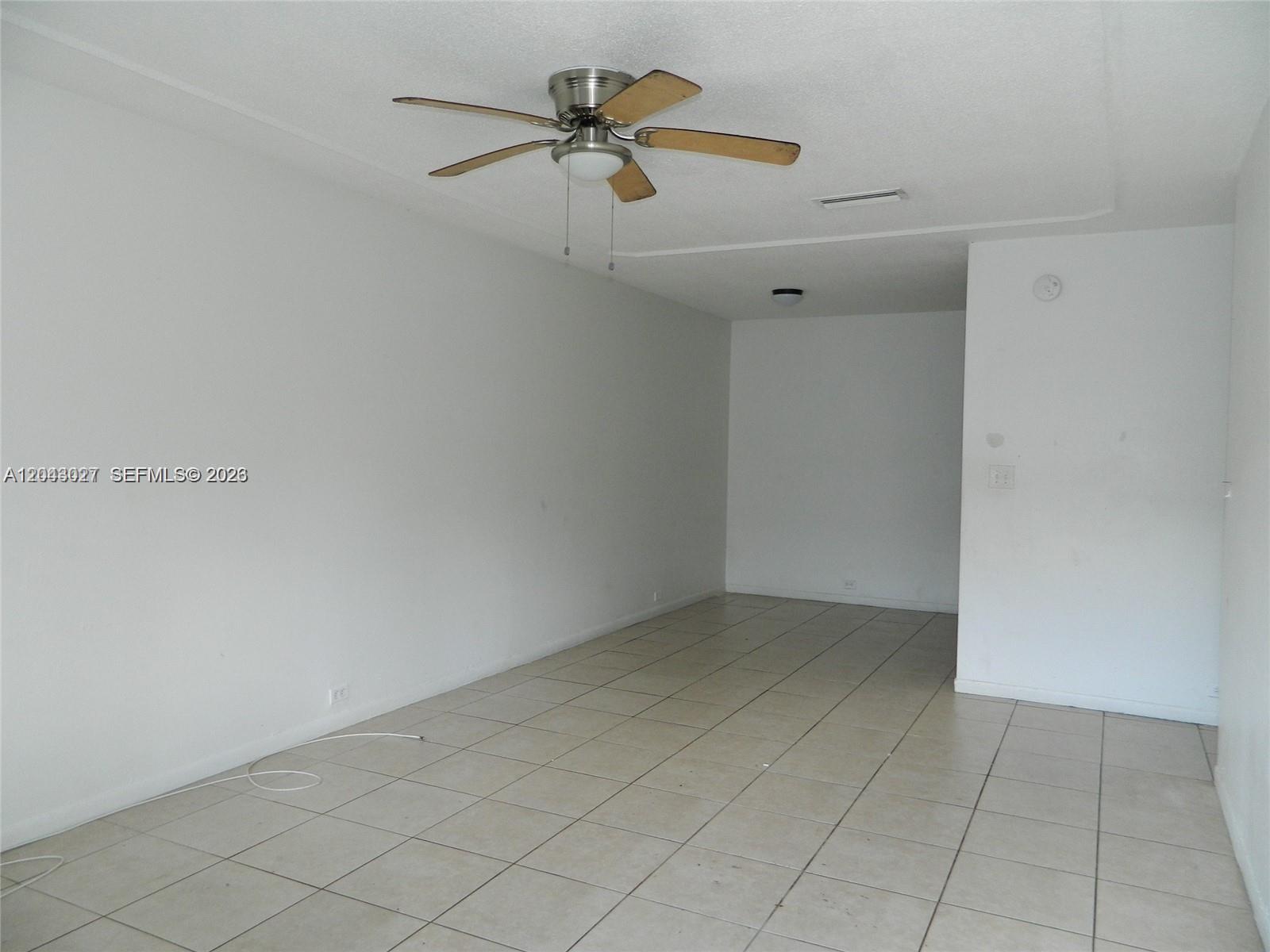 An empty room features white walls, light-colored tile flooring, and a ceiling fan — 1890 NW 58th Ter # 2, Sunrise FL 33313, SUNRISE, FL
