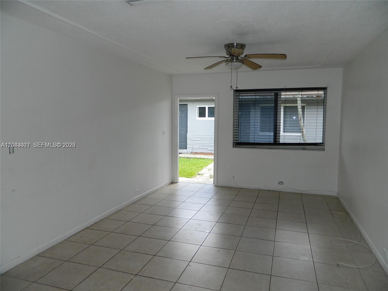 An empty room features white walls, light-colored tile flooring, a ceiling fan, and a doorway — 1890 NW 58th Ter # 2, Sunrise FL 33313, SUNRISE, FL