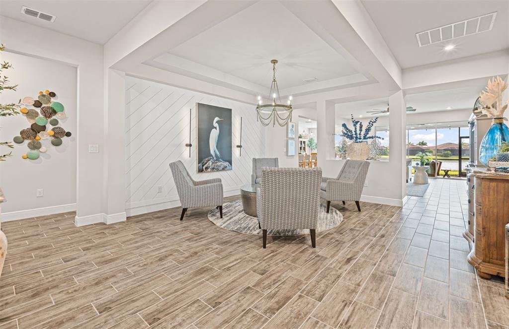 A living area features wood-look tile floors, a coffered ceiling, and a diagonal paneled wall — 20380 SYMPHONY PLACE, VENICE, FL