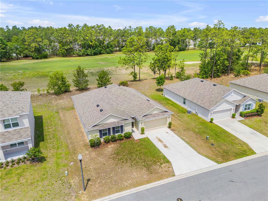 An aerial view shows a suburban house with a driveway and a golf course backyard — 48 HICKORY COURSE, OCALA, FL