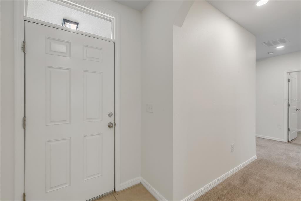 A white front door with a transom window opens into a carpeted entryway — 48 HICKORY COURSE, OCALA, FL