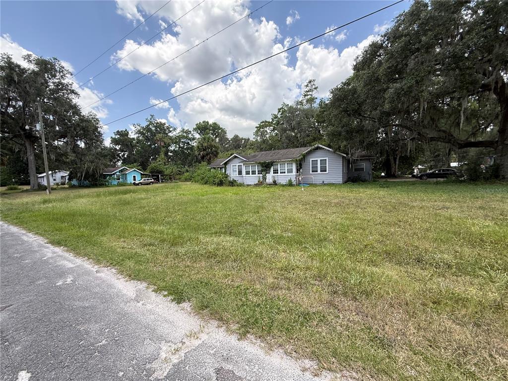 A light gray single-story house sits on a large, grassy lot with mature trees — 4500 SE 18TH AVENUE, OCALA, FL