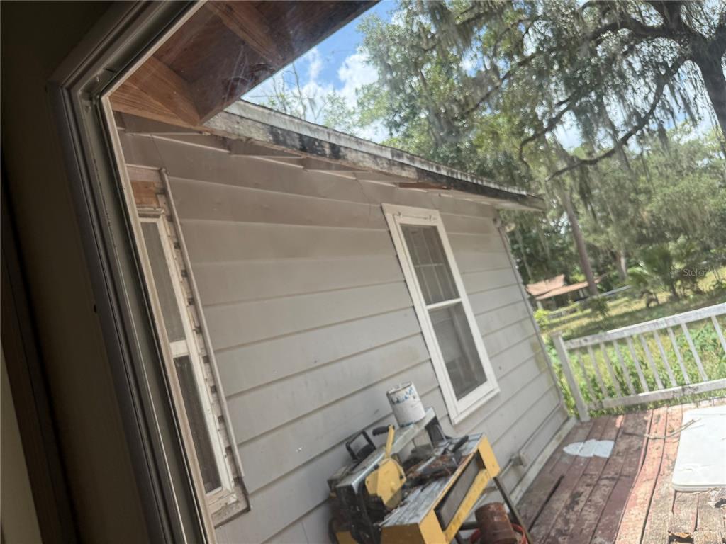 An exterior view of a house with wood siding, a wooden deck, and exposed roof rafters — 4500 SE 18TH AVENUE, OCALA, FL