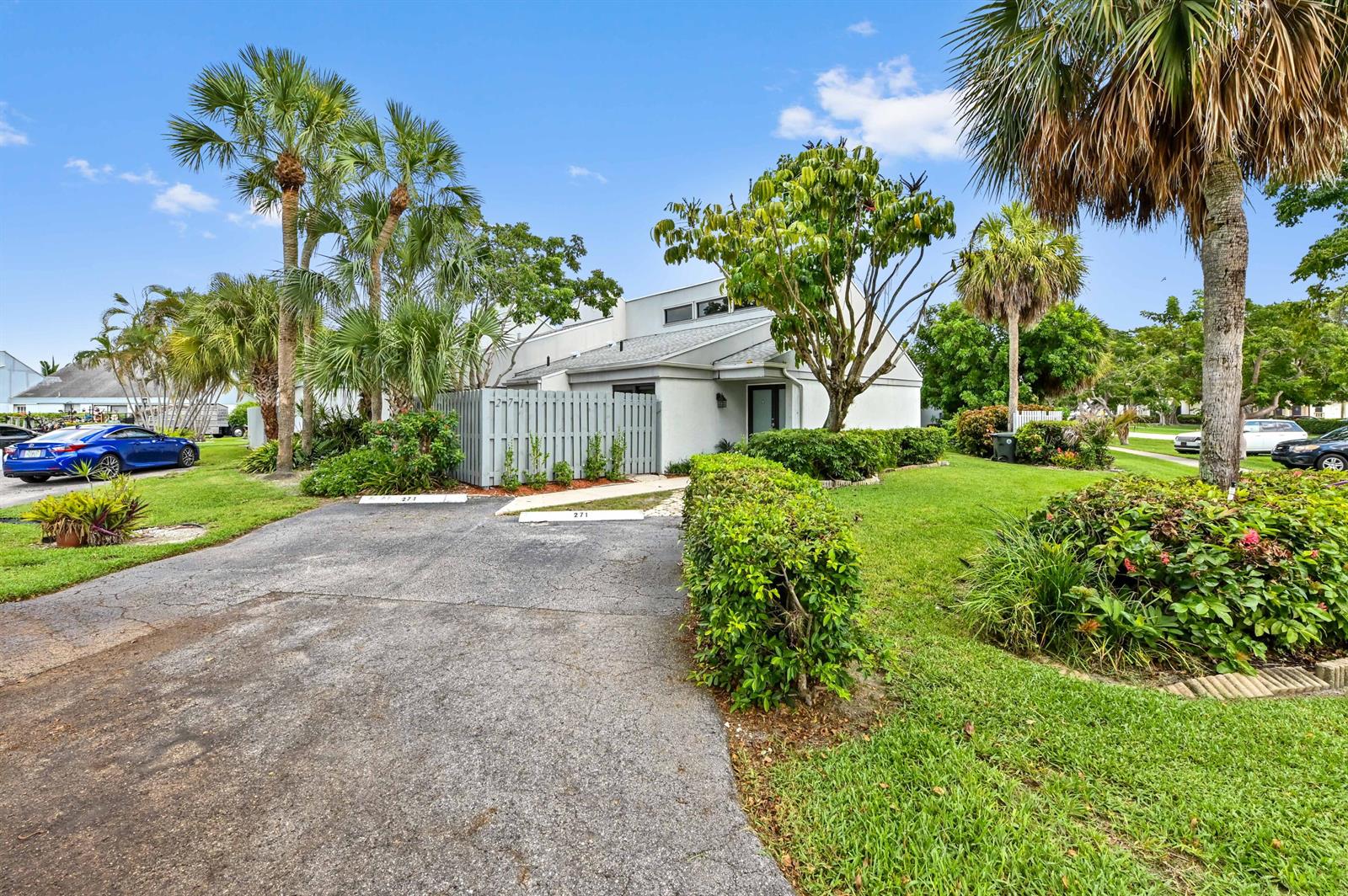 A paved driveway leads to a light-colored townhouse with a gray fence and palm trees — 271 NW 15th Street, Boca Raton FL 33432, BOCA RATON, FL
