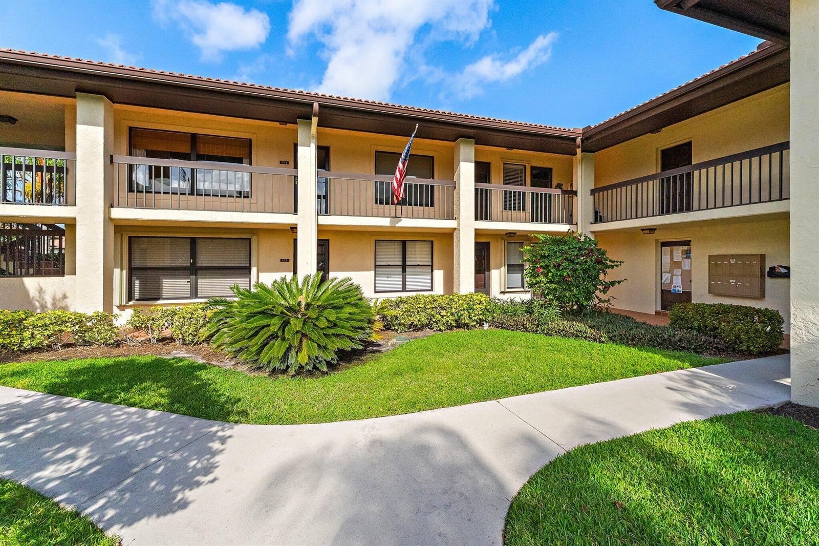 A two-story apartment building with a landscaped courtyard, walkways, and a balcony — 671 SW South River Drive # 105, Stuart FL 34997, STUART, FL