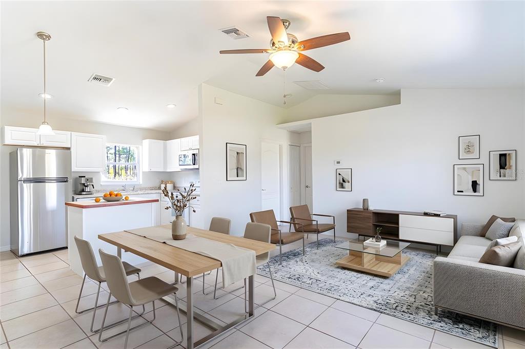An open-concept living and dining area features tile flooring, white cabinetry, and a ceiling fan — 1411 BITTERSWEET STREET, LAKE PLACID, FL