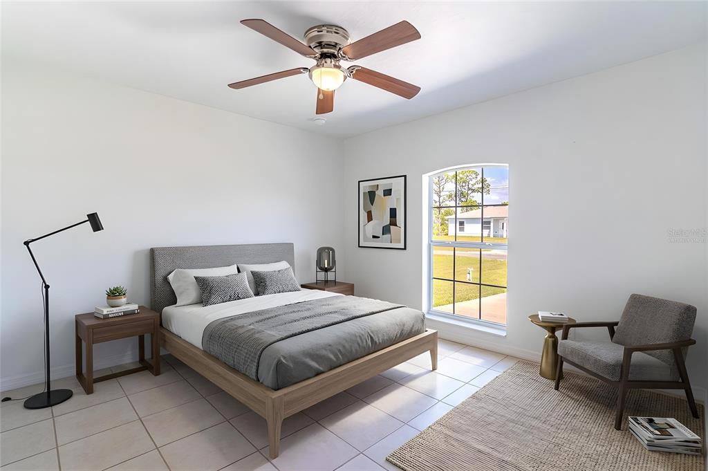 This bedroom features a bed, a ceiling fan, a window, and a chair on tile flooring — 1411 BITTERSWEET STREET, LAKE PLACID, FL