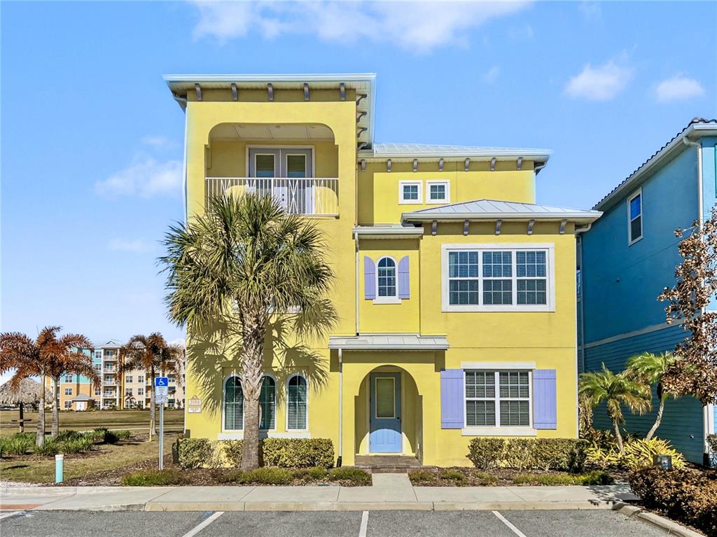 A yellow three-story house with a palm tree in the front yard — 3052 PARROT HEAD PLACE, KISSIMMEE, FL