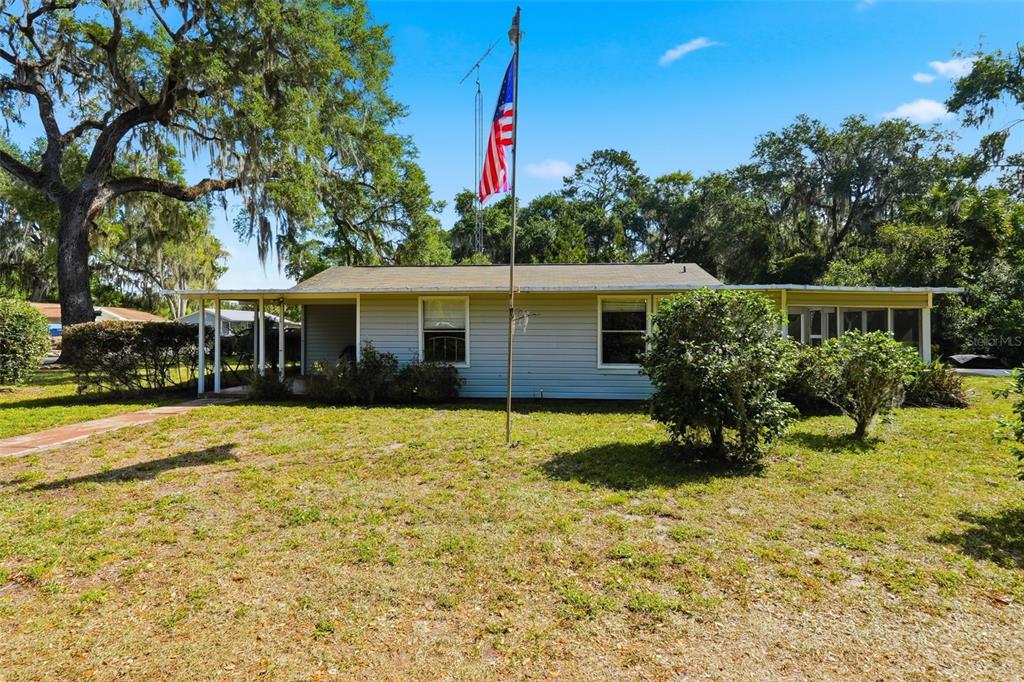 A single-story house with light siding and a flag pole in the front yard — 1289 CR 436, LAKE PANASOFFKEE, FL