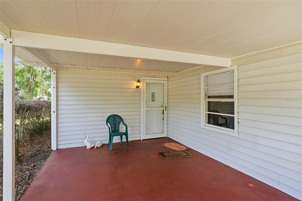 A covered porch with a red concrete floor, white siding, and a single entry door — 1289 CR 436, LAKE PANASOFFKEE, FL