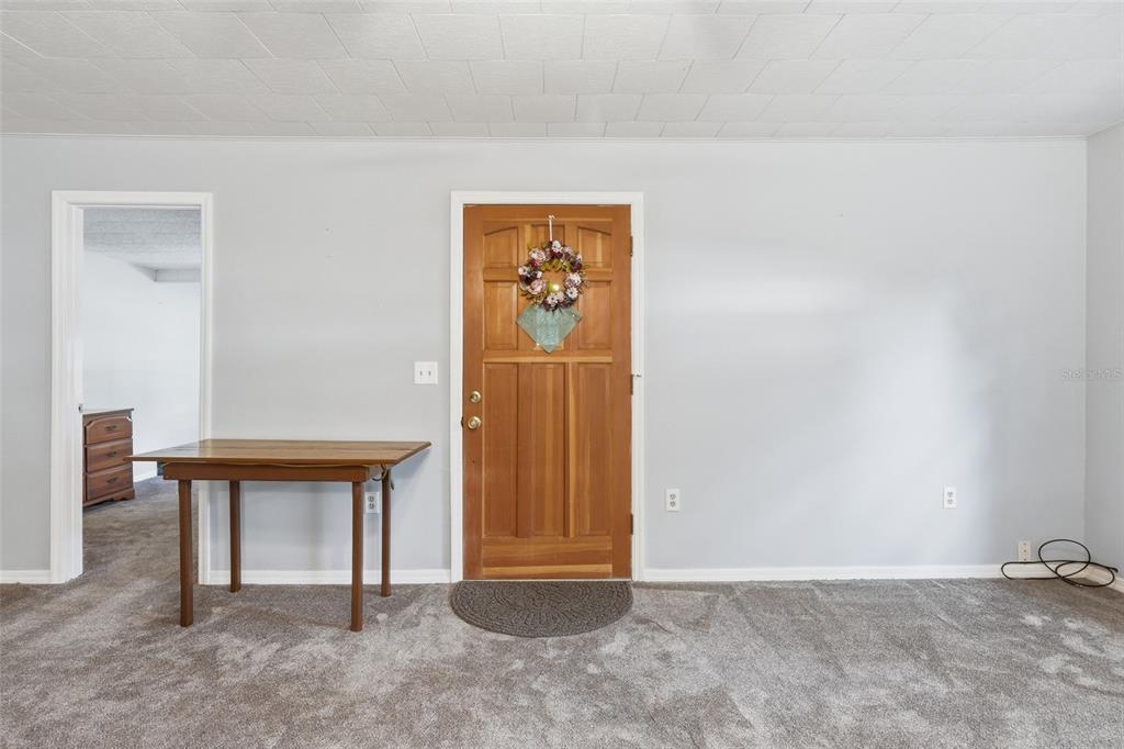 A room with gray carpet, light gray walls, a wooden door, and a folding table — 1289 CR 436, LAKE PANASOFFKEE, FL