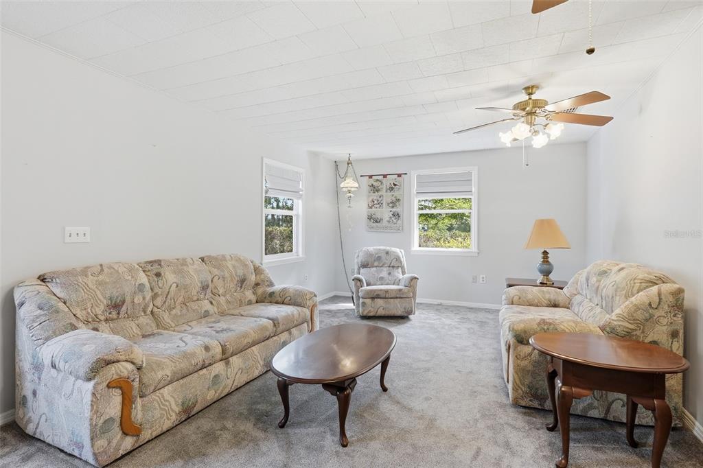 A living room features gray carpeting, two patterned sofas, a recliner, and a ceiling fan — 1289 CR 436, LAKE PANASOFFKEE, FL