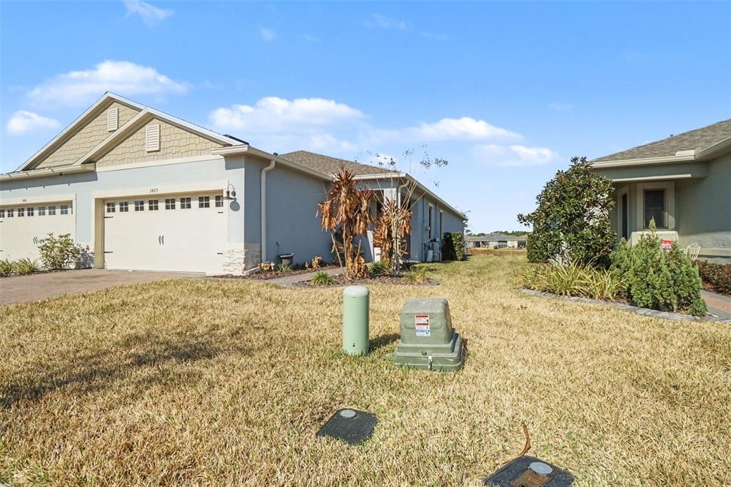 A view of the exterior of two adjacent suburban houses with a grassy front yard — 3465 MEADOW BEAUTY WAY, CLERMONT, FL