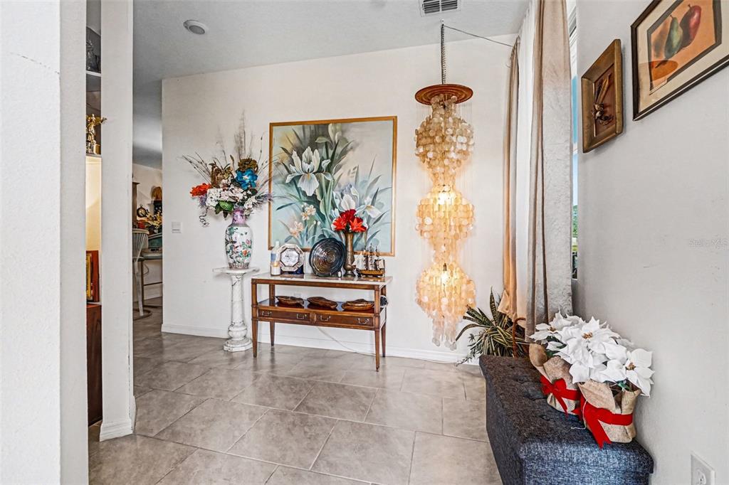 An entryway features tile flooring, a decorative chandelier, a console table, and wall art — 3465 MEADOW BEAUTY WAY, CLERMONT, FL