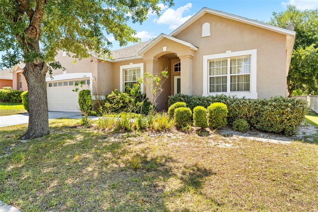 A single-story tan stucco house features a two-car garage, arched entryway, and landscaped front yard — 4211 BLAKEMORE PLACE, SPRING HILL, FL