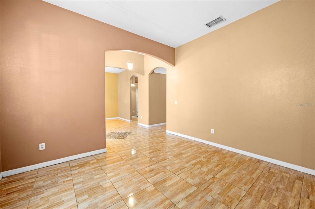 An empty room with tan walls, light-colored tile flooring, and an arched entryway — 4211 BLAKEMORE PLACE, SPRING HILL, FL