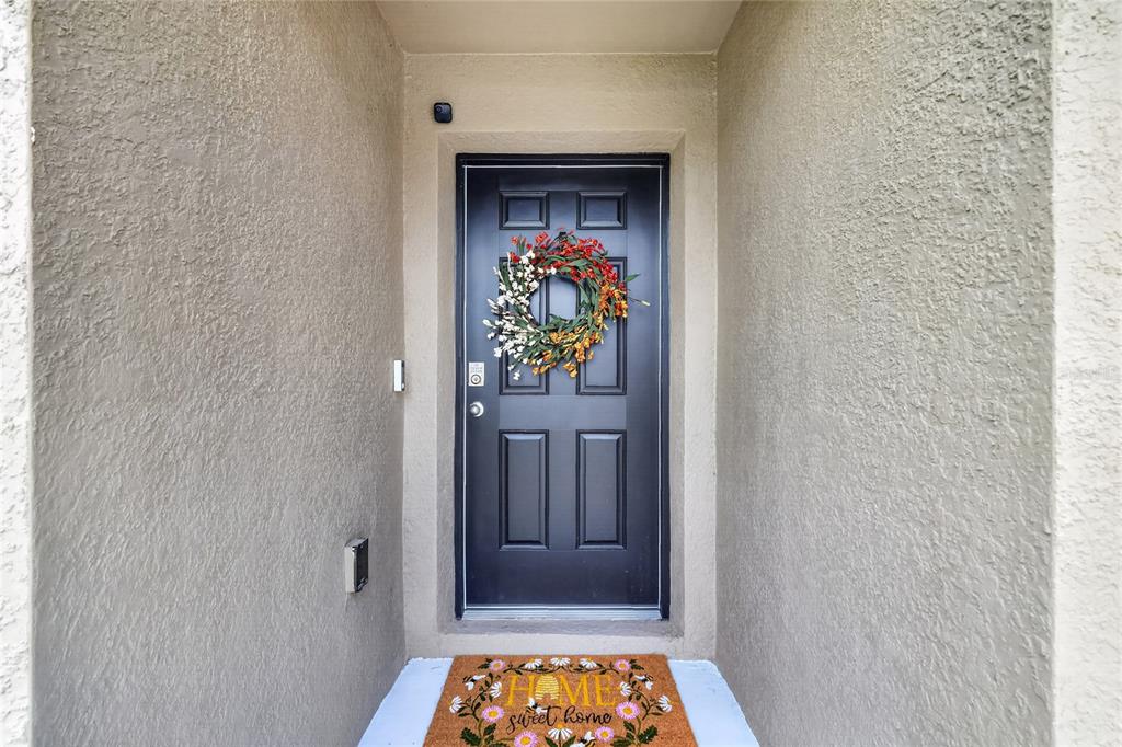 A black front door with a fall wreath sits in a recessed entryway — 10342 SE 162ND PLACE ROAD, SUMMERFIELD, FL
