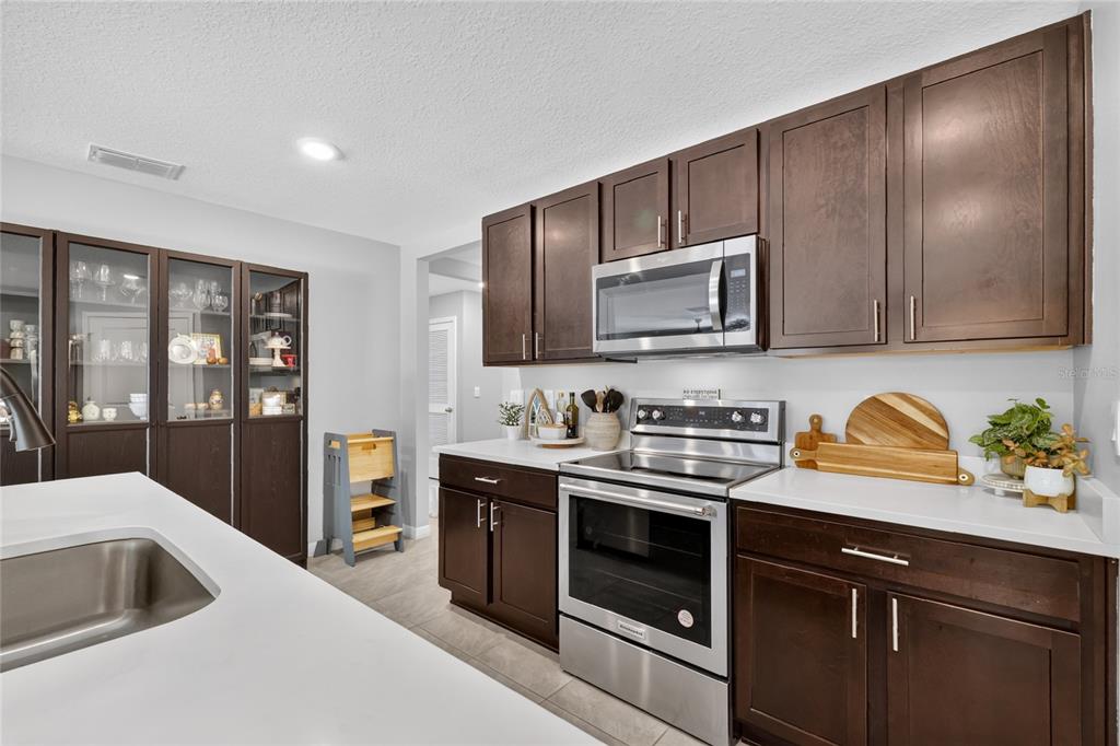 A kitchen features dark wood cabinets, stainless steel appliances, and white countertops — 10342 SE 162ND PLACE ROAD, SUMMERFIELD, FL