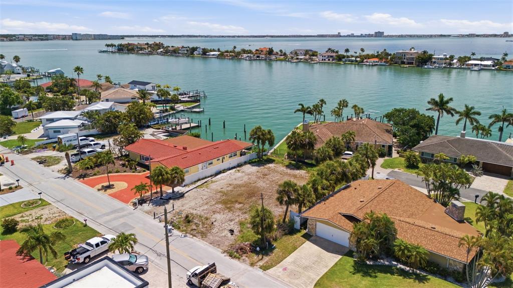 An aerial view shows a vacant waterfront lot situated between two houses near a bay — 620 59TH AVENUE, ST PETE BEACH, FL