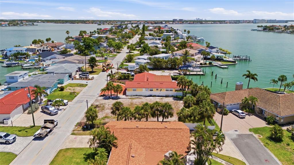 An aerial view shows waterfront homes with red-tiled roofs along a narrow residential street — 620 59TH AVENUE, ST PETE BEACH, FL