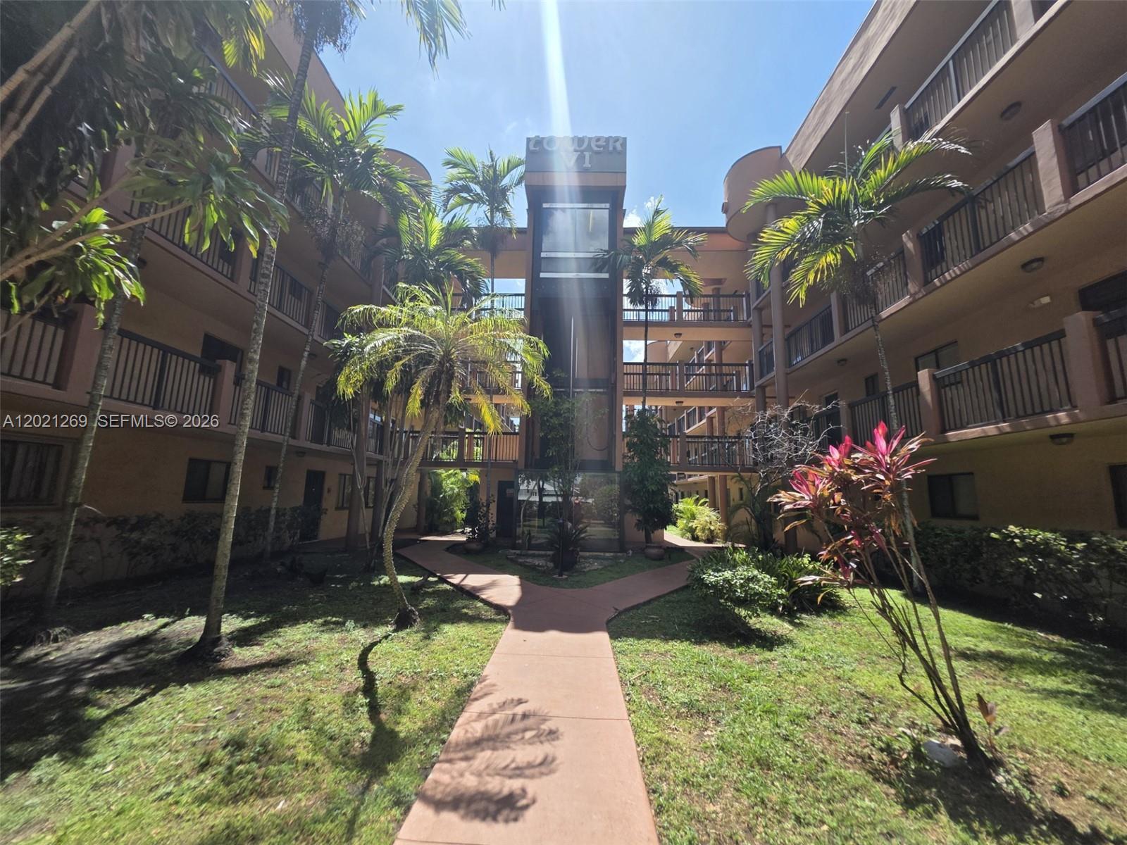 A courtyard with a paved walkway leads to the entrance of a multi-story apartment building — 5560 W 21st Ct # 308, Hialeah FL 33016, HIALEAH, FL