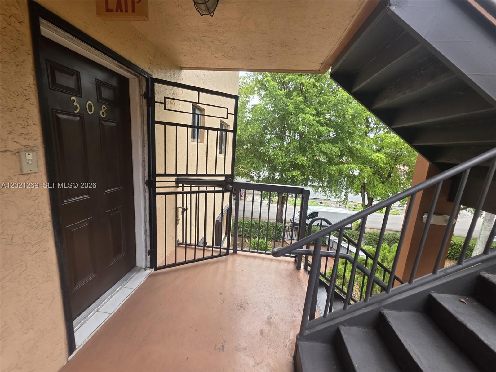 An exterior view of an apartment entrance with a metal security gate and staircase — 5560 W 21st Ct # 308, Hialeah FL 33016, HIALEAH, FL
