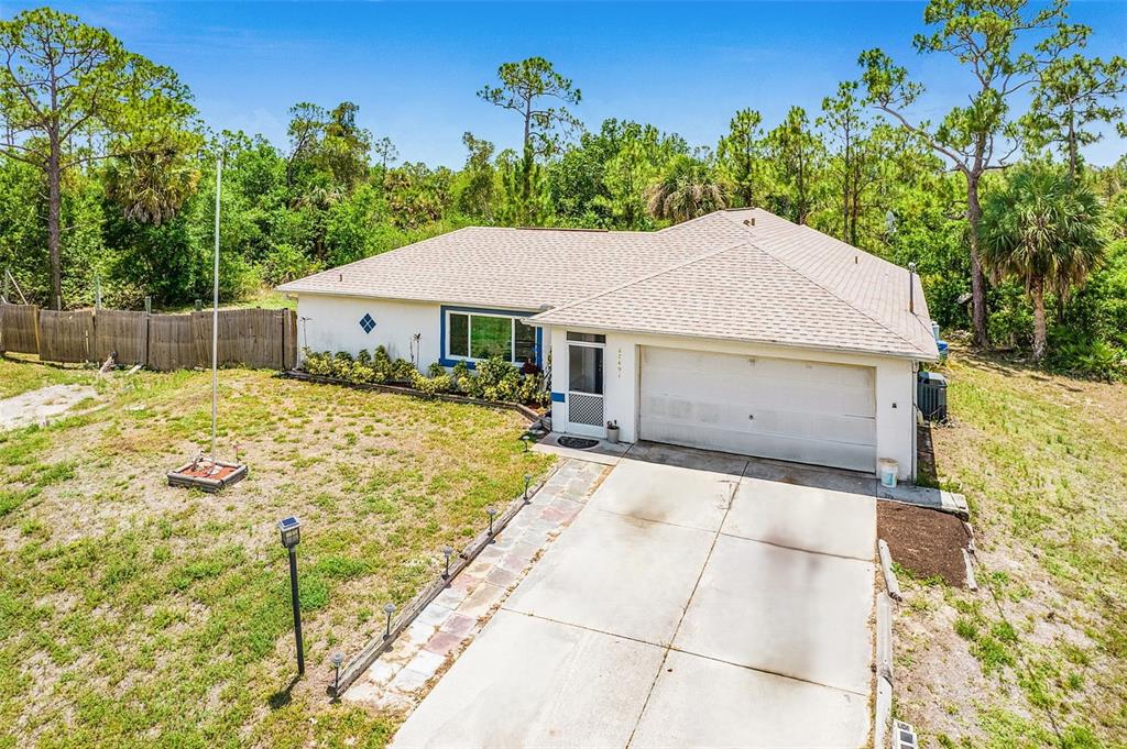 An aerial view of a single-story house with a white exterior, garage, and driveway — 27491 LAS LOMAS DRIVE, PUNTA GORDA, FL