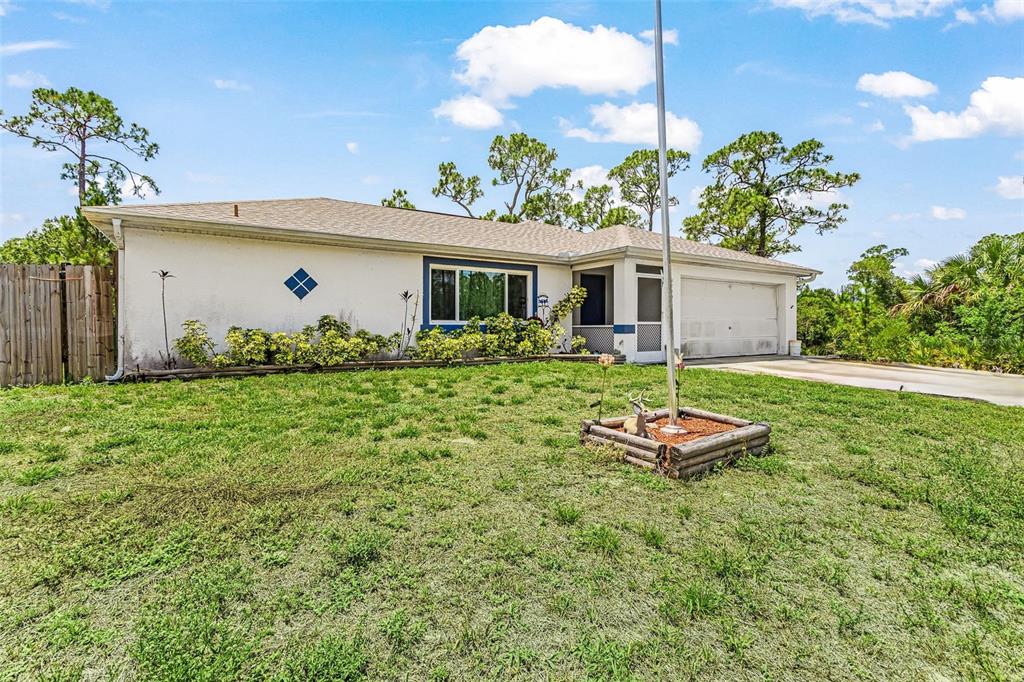 A single-story house with a white stucco exterior, a garage, and a front yard — 27491 LAS LOMAS DRIVE, PUNTA GORDA, FL