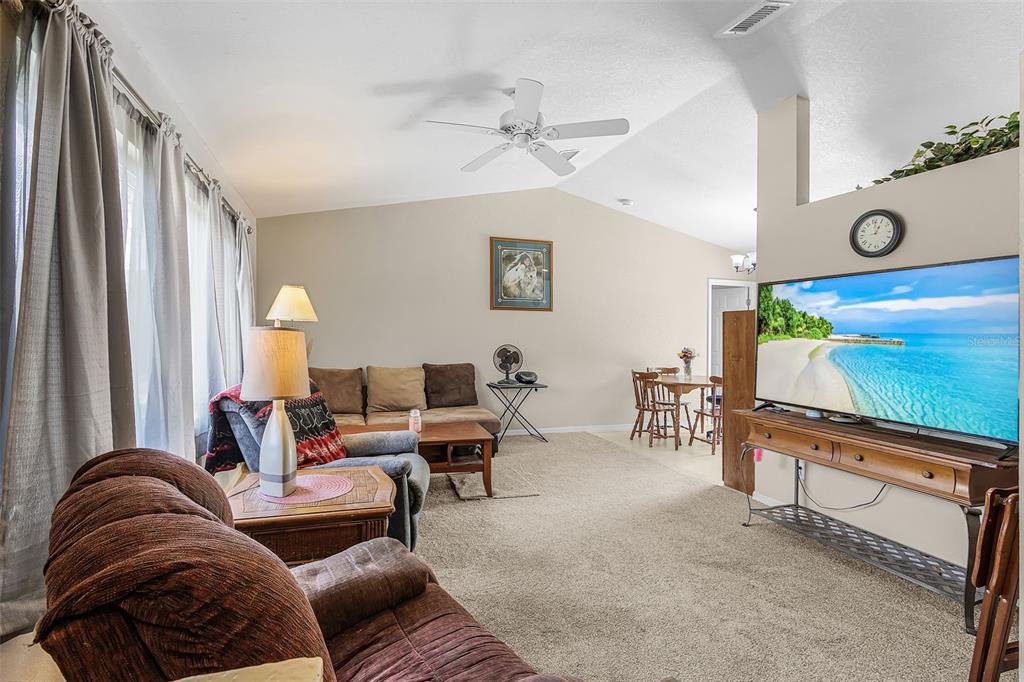 A living room with carpeted floors, a ceiling fan, and a television on a console — 27491 LAS LOMAS DRIVE, PUNTA GORDA, FL