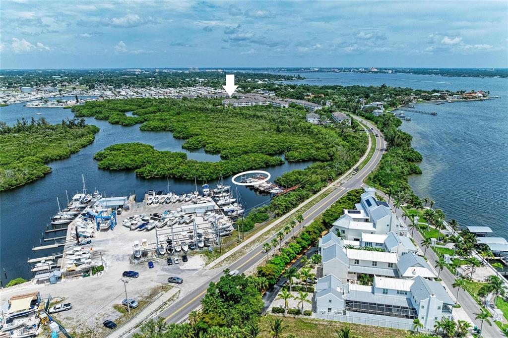 An aerial view shows a marina, a coastal road, and residential buildings near mangroves — 3206 10TH LN W, PALMETTO, FL