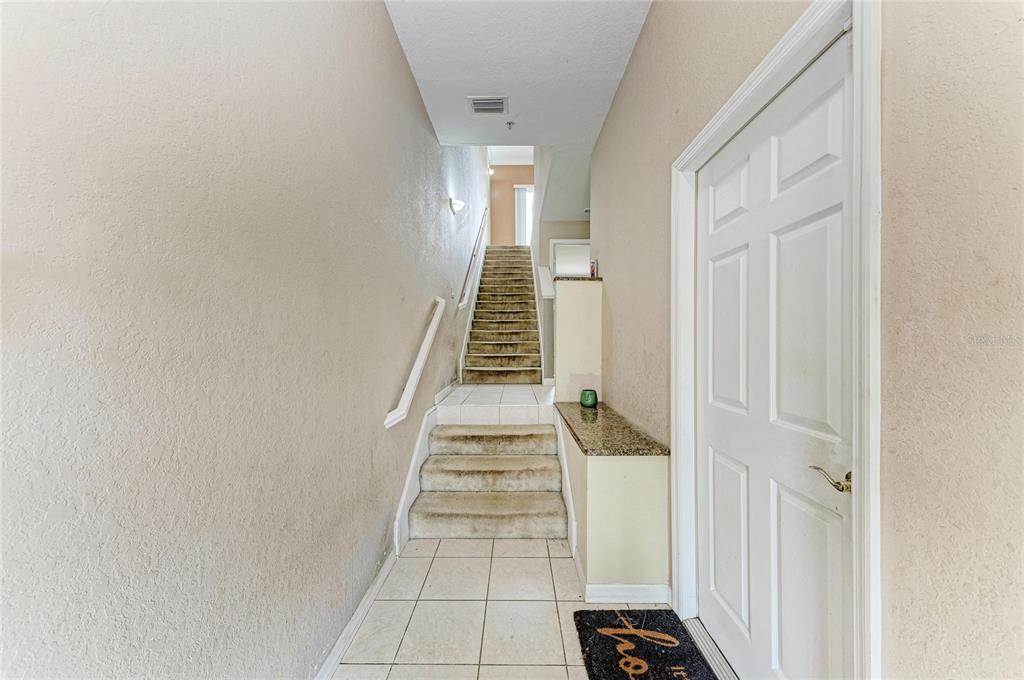 A tiled entryway features carpeted stairs leading upward and a white door on the right — 3206 10TH LN W, PALMETTO, FL
