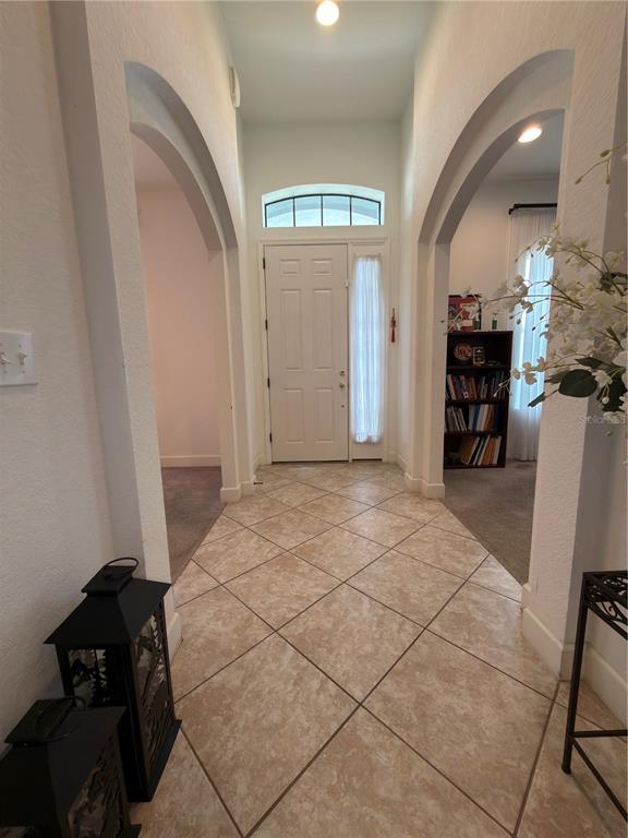 A tiled entryway features arched openings leading to adjacent rooms and a white front door — 4086 DINNER LAKE WAY, LAKE WALES, FL