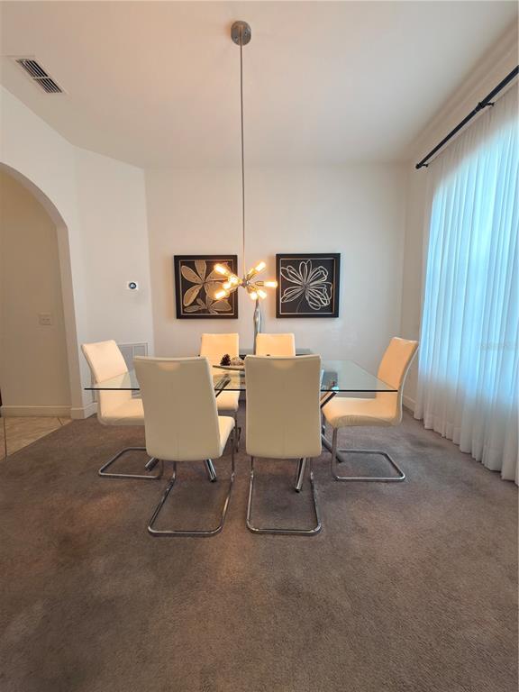 A dining room features a glass-topped table, six white chairs, and a modern chandelier — 4086 DINNER LAKE WAY, LAKE WALES, FL