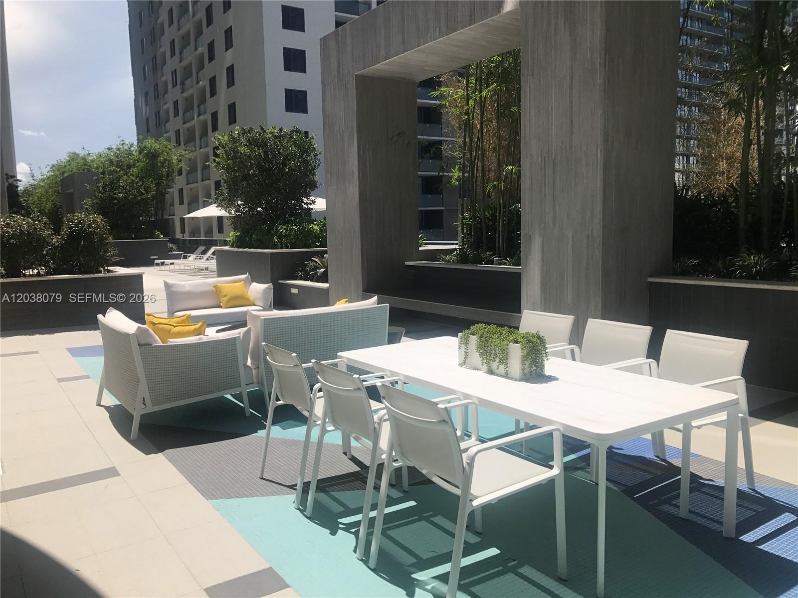An outdoor patio features a dining set and lounge furniture on a patterned blue rug — 55 SW 9th St # 1607, Miami FL 33130, MIAMI, FL