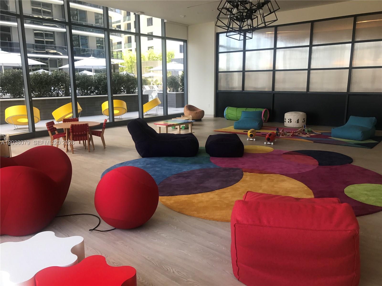 A colorful children's playroom features beanbag chairs, a patterned rug, and floor-to-ceiling windows — 55 SW 9th St # 1607, Miami FL 33130, MIAMI, FL