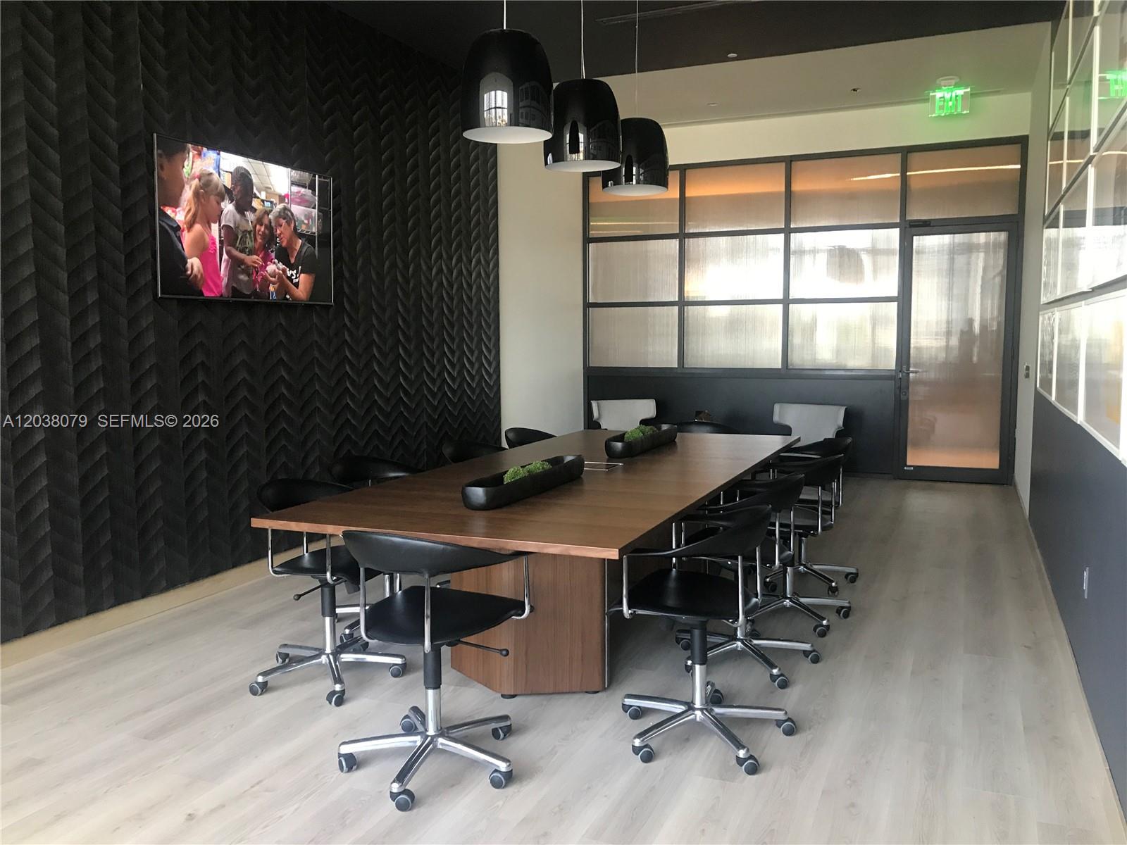 A modern conference room features a long wooden table, black chairs, and textured wall panels — 55 SW 9th St # 1607, Miami FL 33130, MIAMI, FL