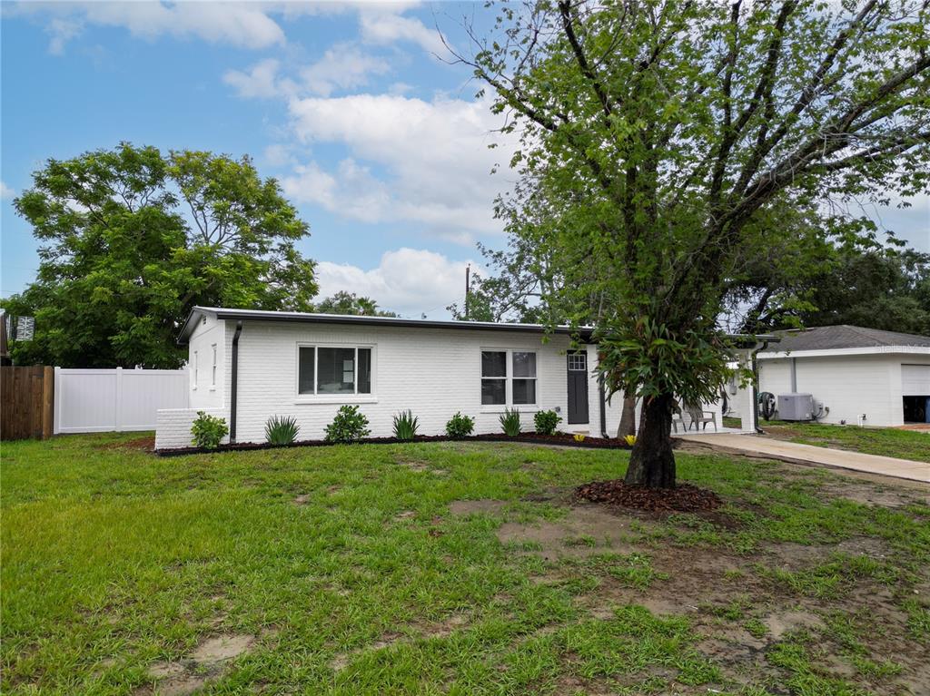 A white, single-story brick house with a front lawn and a large tree — 11309 115TH STREET, LARGO, FL