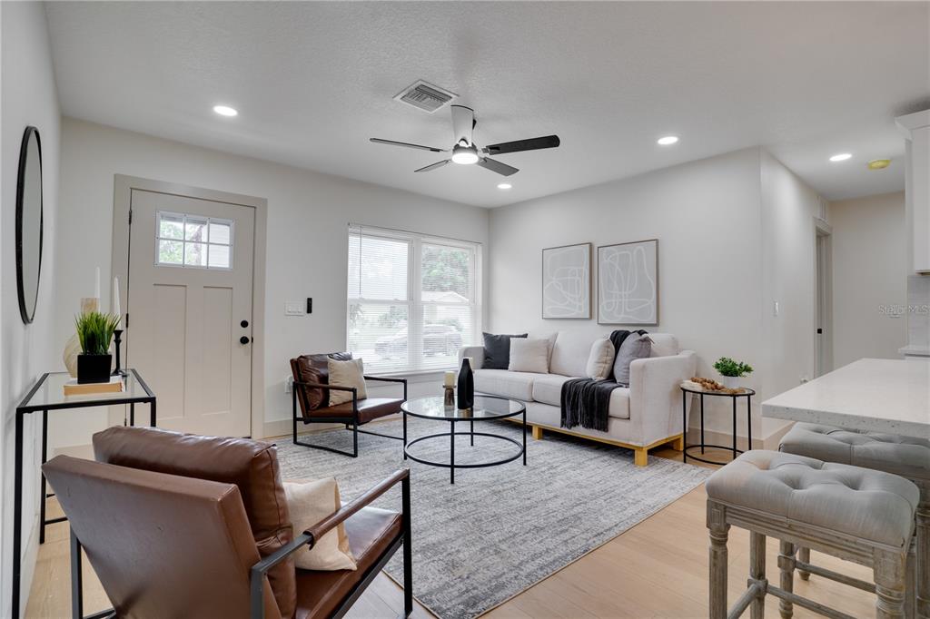 A modern living room features a white sofa, two leather chairs, and a round coffee table — 11309 115TH STREET, LARGO, FL