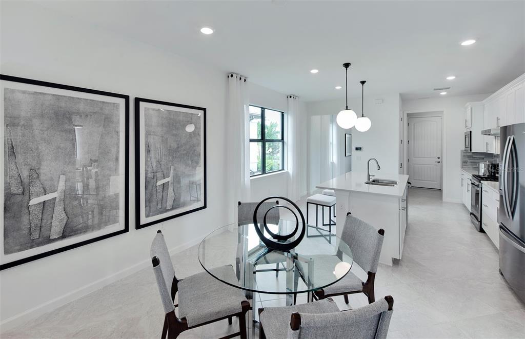 A dining area with a glass table and chairs sits adjacent to a white kitchen — 4739 BLUE STAR COURT, NORTH PORT, FL