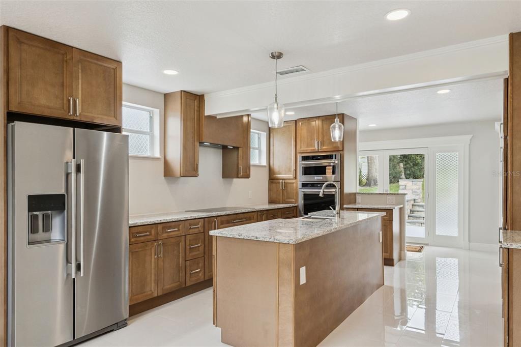 A kitchen with wood cabinets, granite countertops, stainless steel appliances, and a central island — 2316 N GRIFFIN DRIVE, LEESBURG, FL