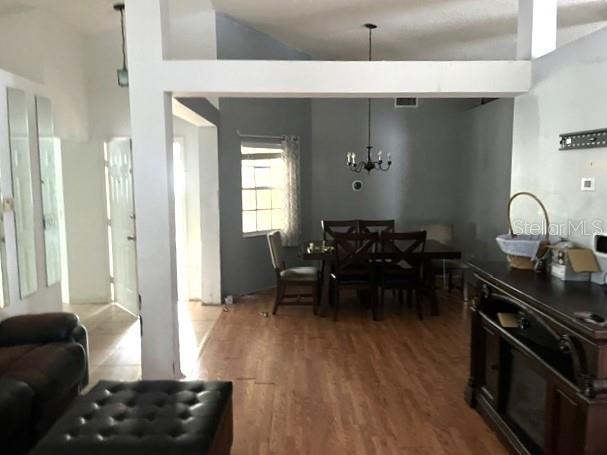 A dining area with a wooden table and chairs sits behind a living room space — 26 SAINT KITTS CIRCLE, WINTER HAVEN, FL