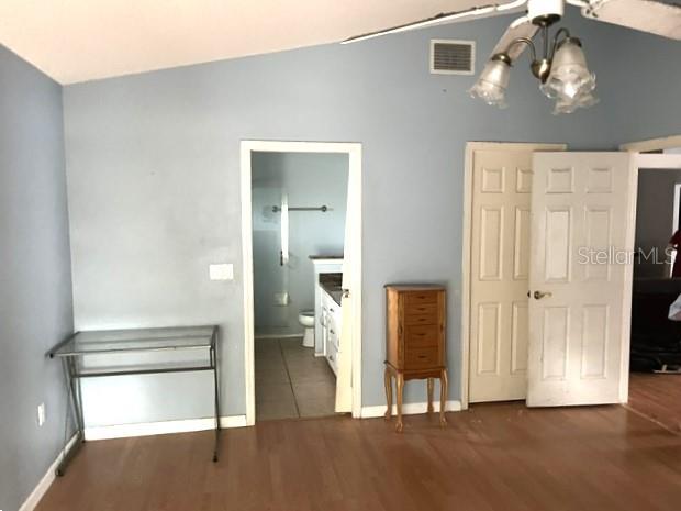 A room with light blue walls, wood flooring, a glass desk, and a doorway to a bathroom — 26 SAINT KITTS CIRCLE, WINTER HAVEN, FL