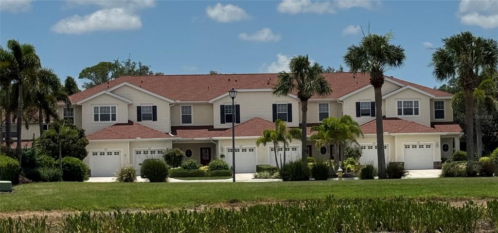A multi-unit residential building with beige siding, red shingled roofs, and several garage doors — JONAH DRIVE, NORTH PORT, FL