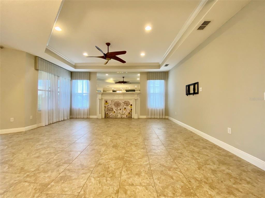 A spacious living room features tile flooring, a tray ceiling, and a fireplace with mirrors — 16238 WIND VIEW LANE, WINTER GARDEN, FL
