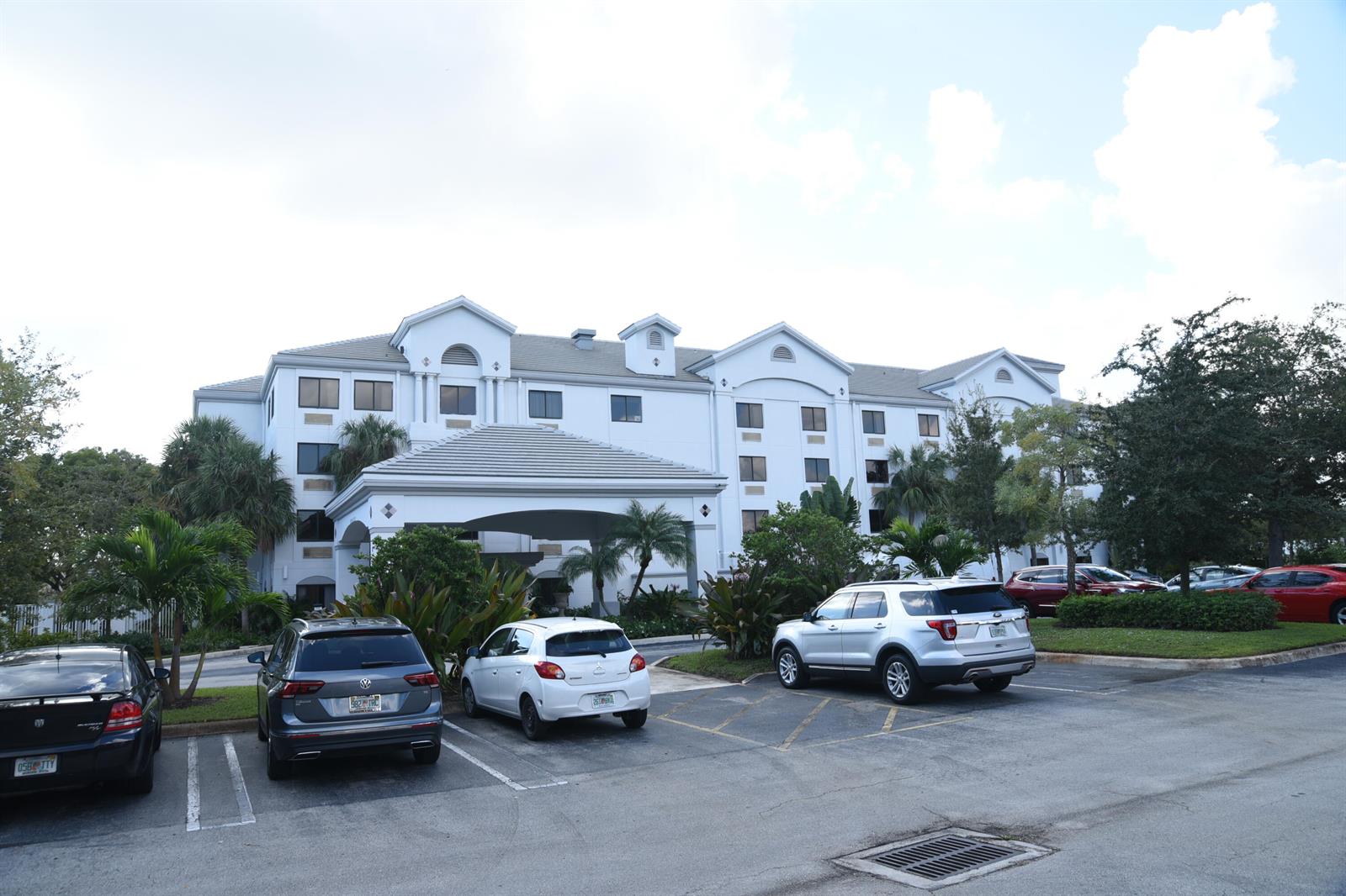 A multi-story white hotel building features a covered entrance and a paved parking lot — 7051 N Seacrest Boulevard, Lantana FL 33462, LANTANA, FL