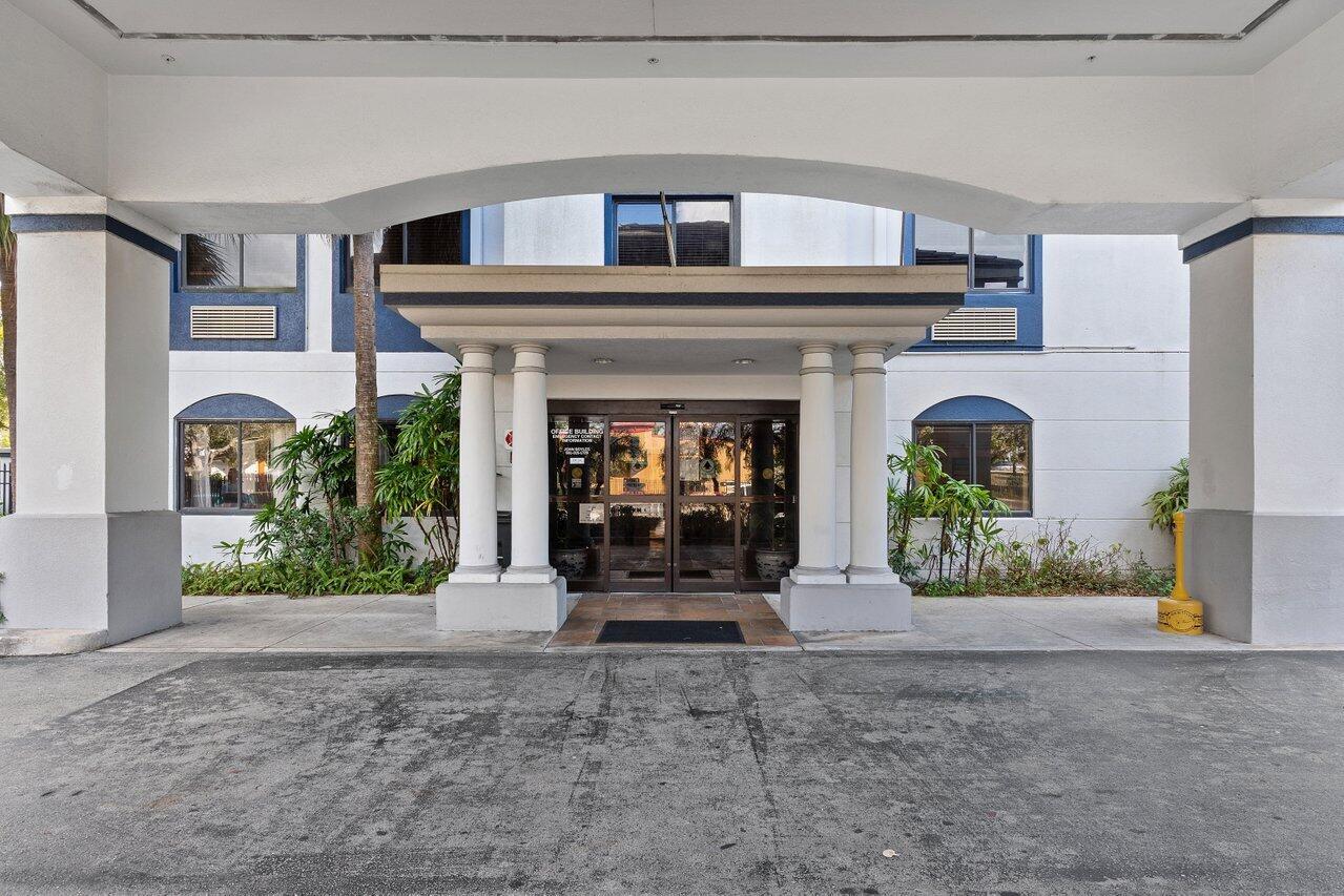 The exterior entrance of a building features a covered portico with white columns and glass doors — 7051 N Seacrest Boulevard, Lantana FL 33462, LANTANA, FL