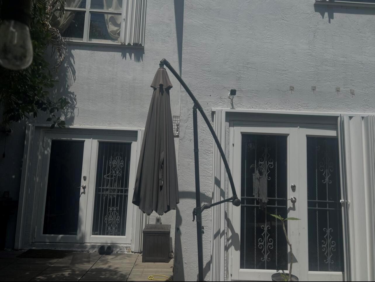 A patio area features a closed cantilever umbrella, white double doors, and tiled flooring — MIAMI GARDENS, FL