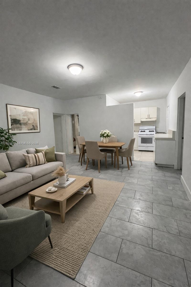 An open-concept living and dining area features gray tile flooring and a neutral color palette — 413 NW 33rd St # A, Miami FL 33127, MIAMI, FL